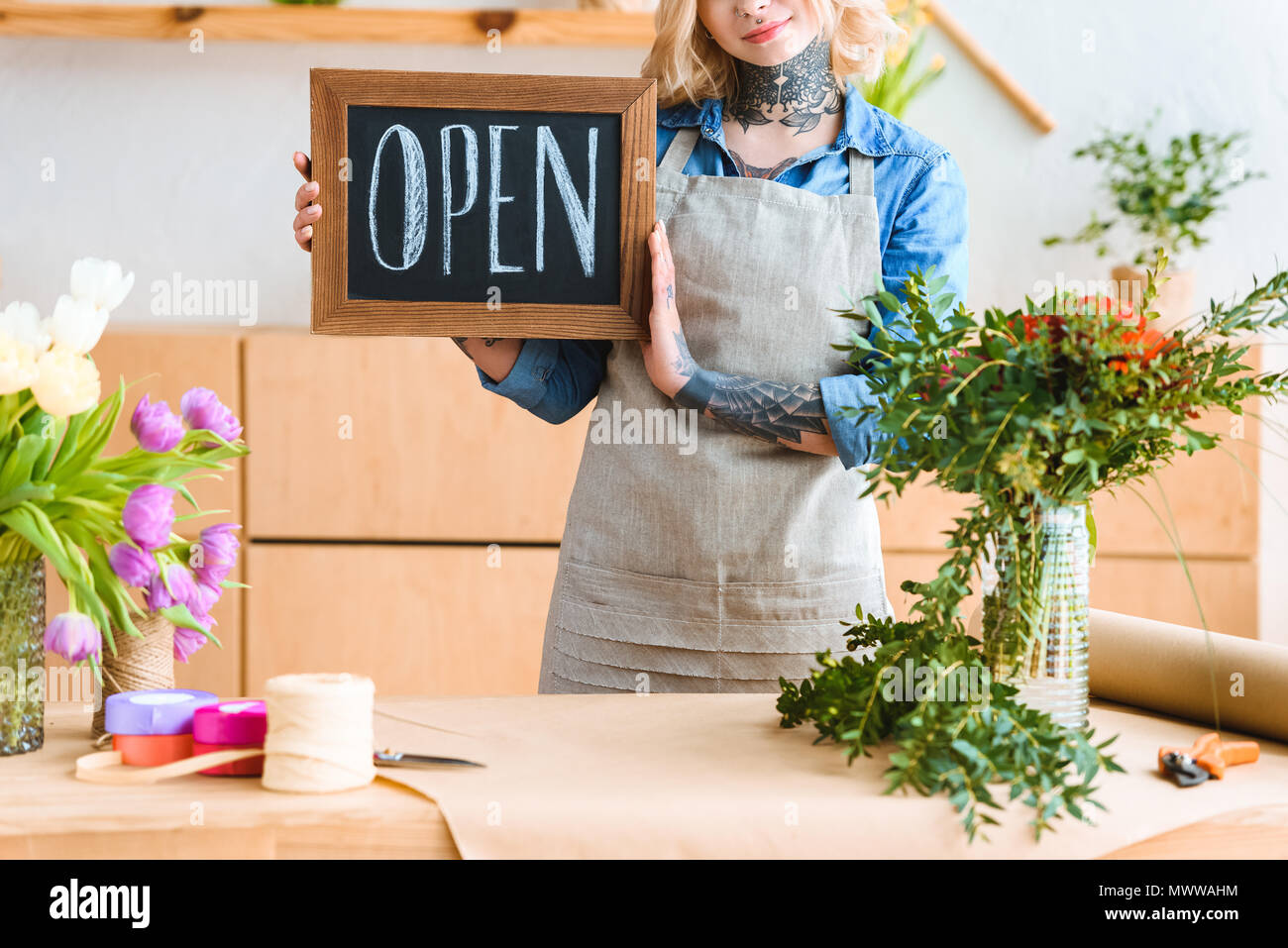 cropped shot of smiling young florist holding sign open in flower shop Stock Photo