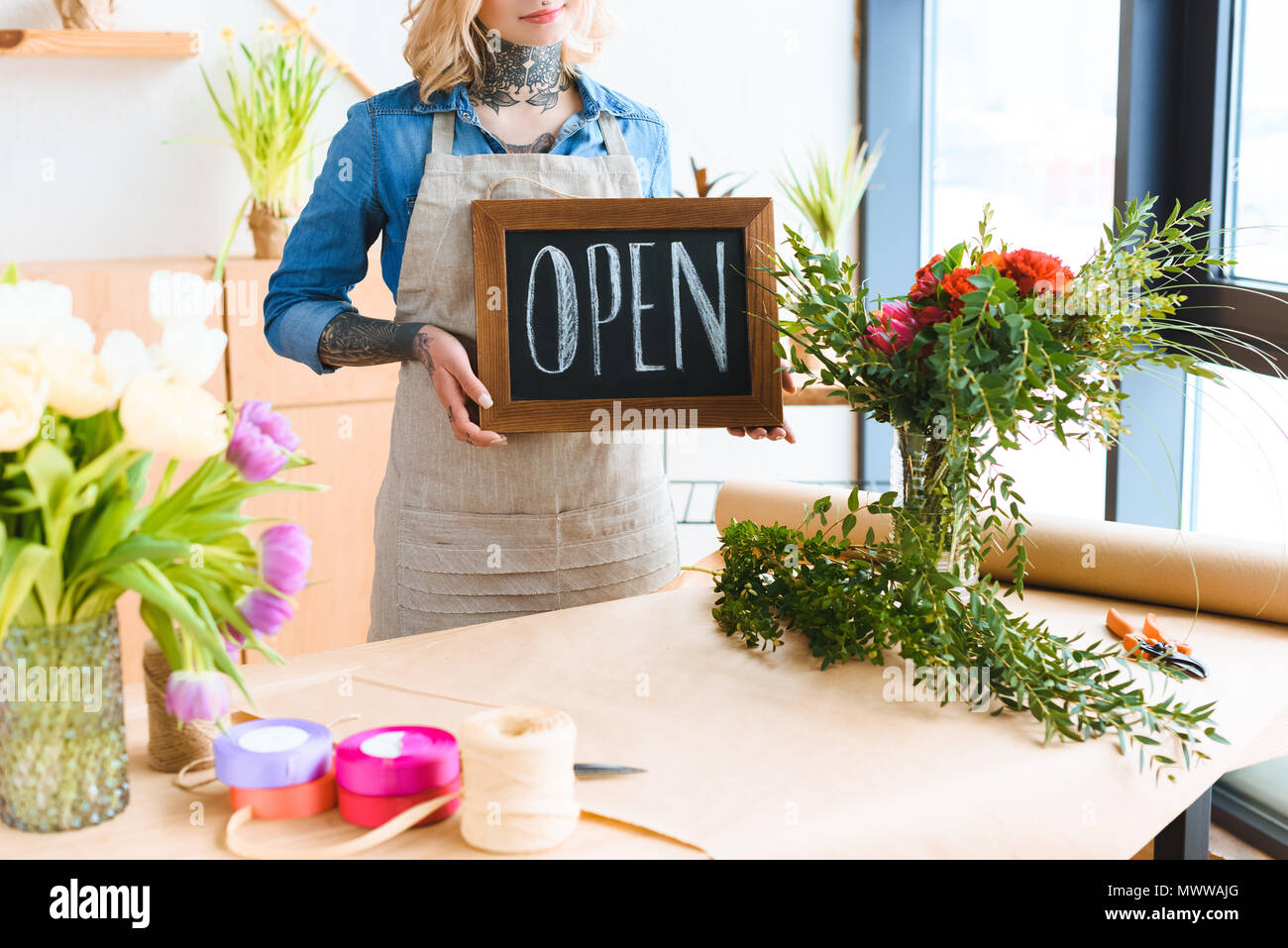 cropped shot of young florist holding open sign in flower shop Stock Photo