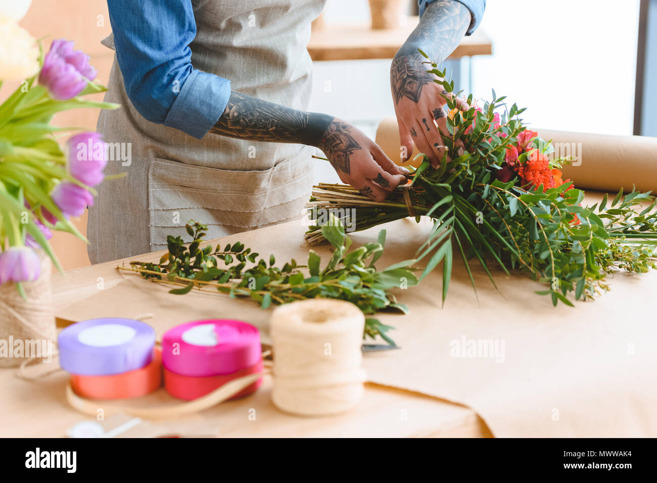 cropped shot of young florist with tattooed hands arranging flower bouquet at workplace Stock Photo