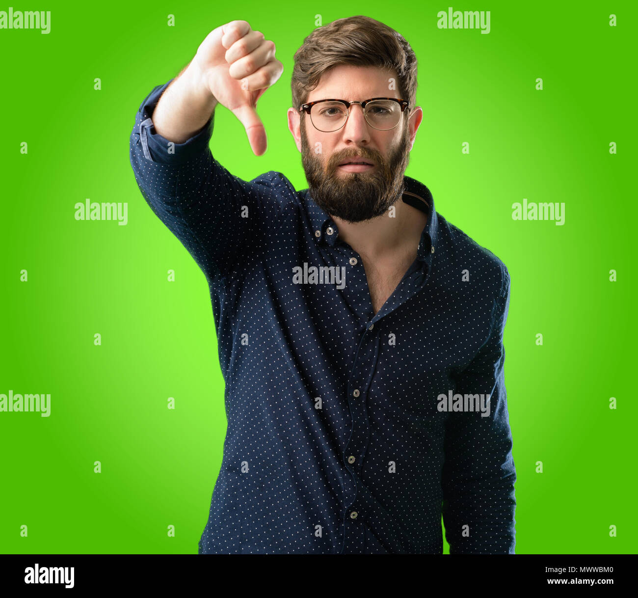 Young hipster man with big beard showing thumbs down unhappy sign of ...