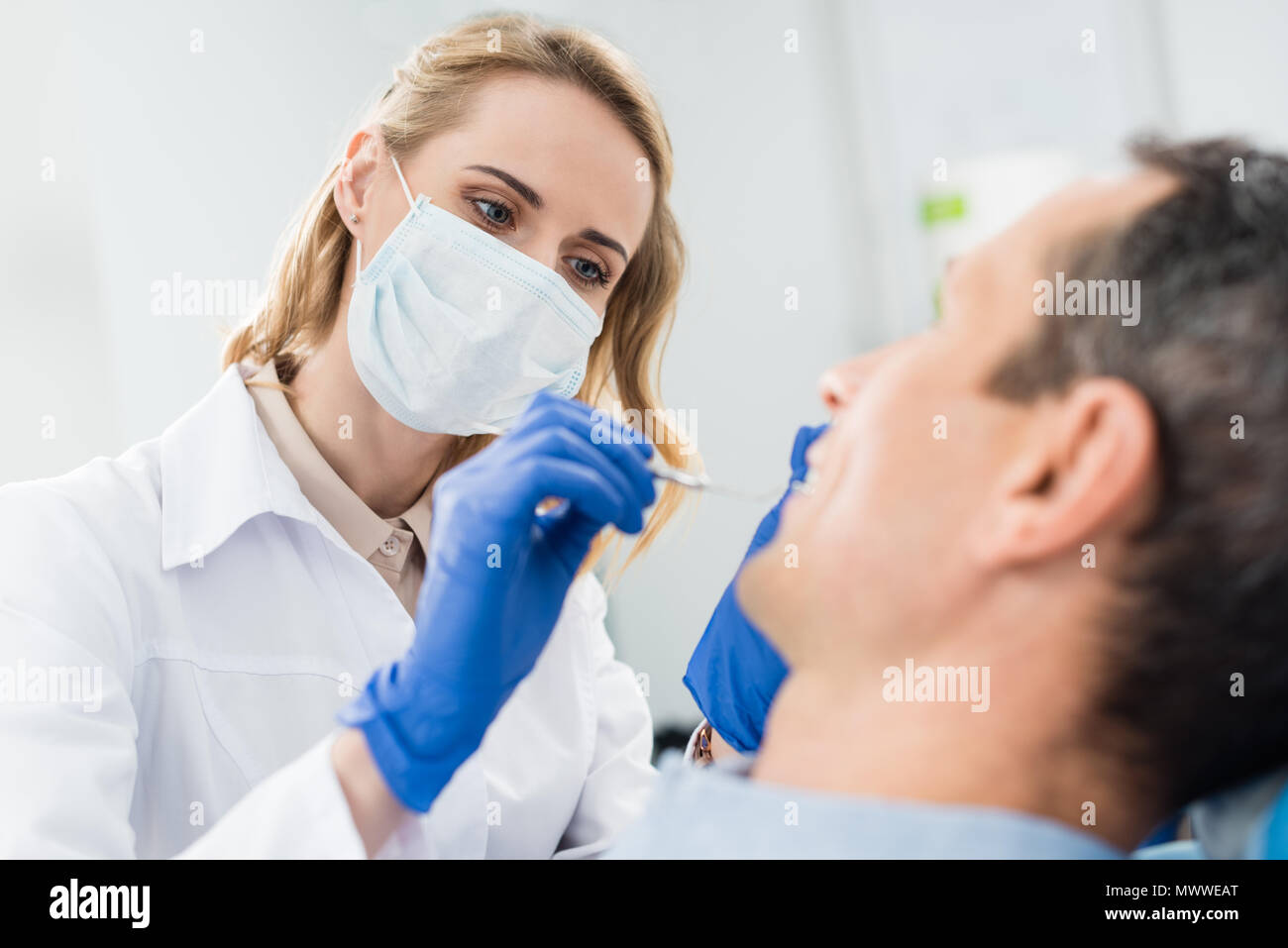 Doctor checking patient teeth with mirror in modern dental clinic Stock