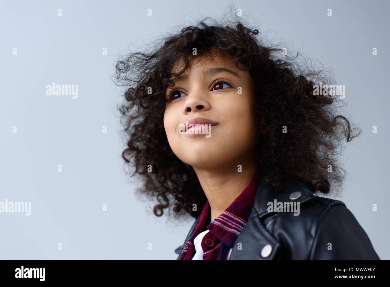 Close Up Portrait Of Little Child With Curly Hair Isolated On Grey