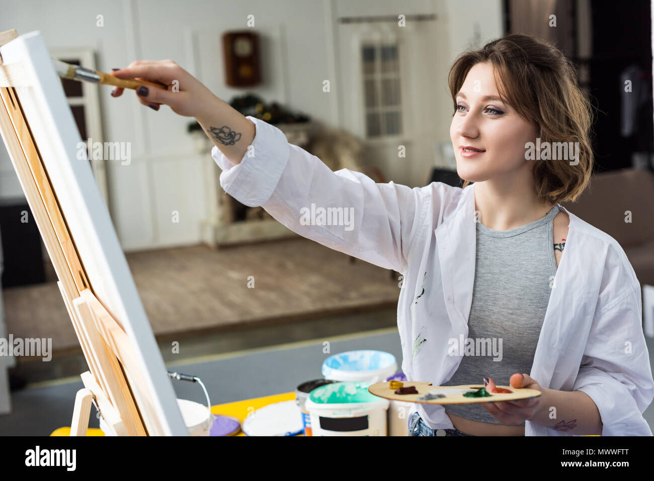 Young inspired girl working by easel in light studio Stock Photo - Alamy