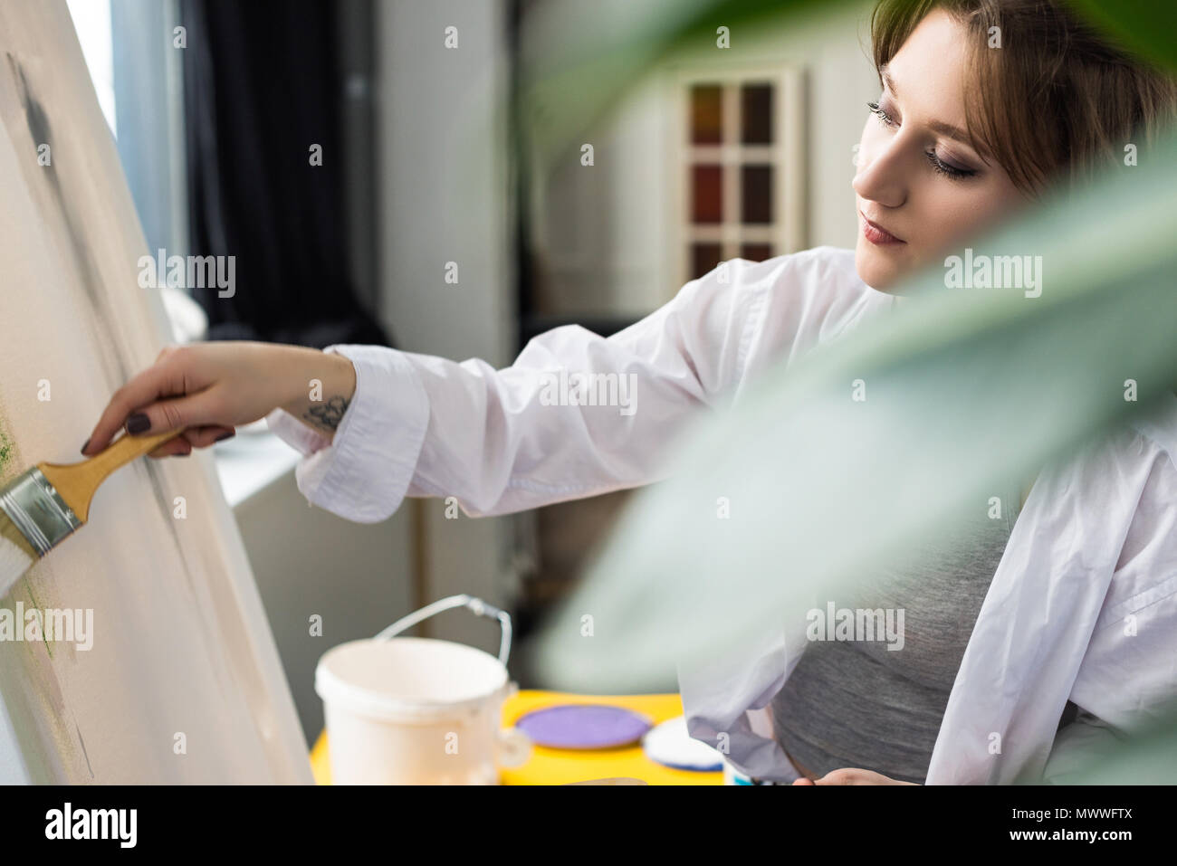 Young artistic girl painting at easel in light studio Stock Photo - Alamy
