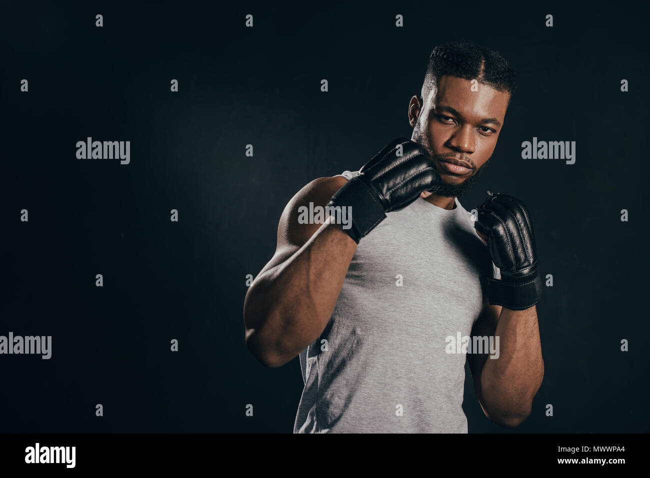 young african american kickboxer in gloves looking at camera isolated ...