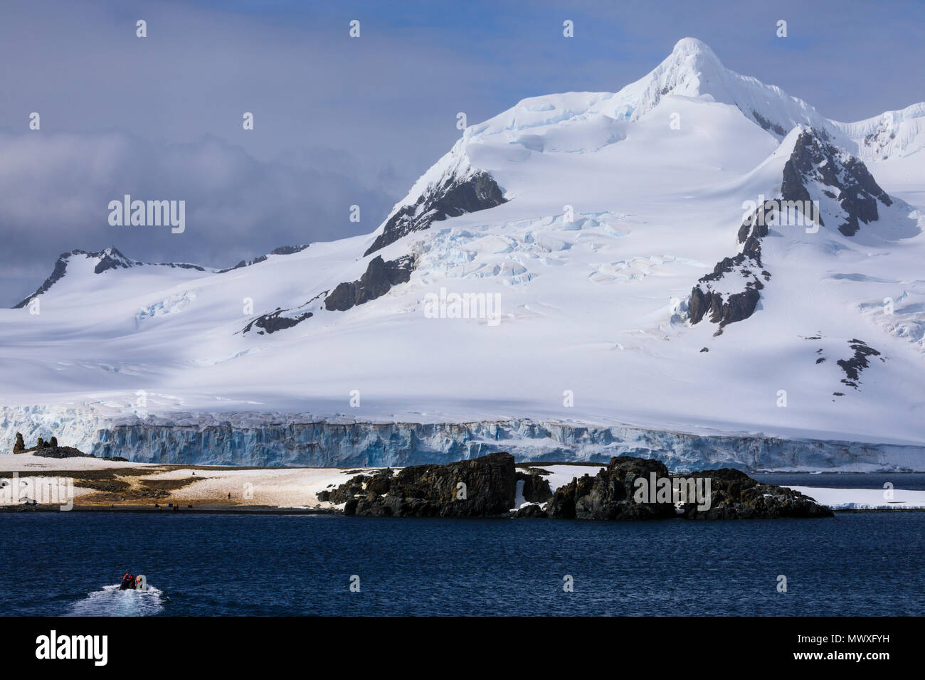 Tourists on a zodiac boat approach Half Moon Island, Livingston Island mountain backdrop, South Shetland Islands, Antarctica, Polar Regions Stock Photo