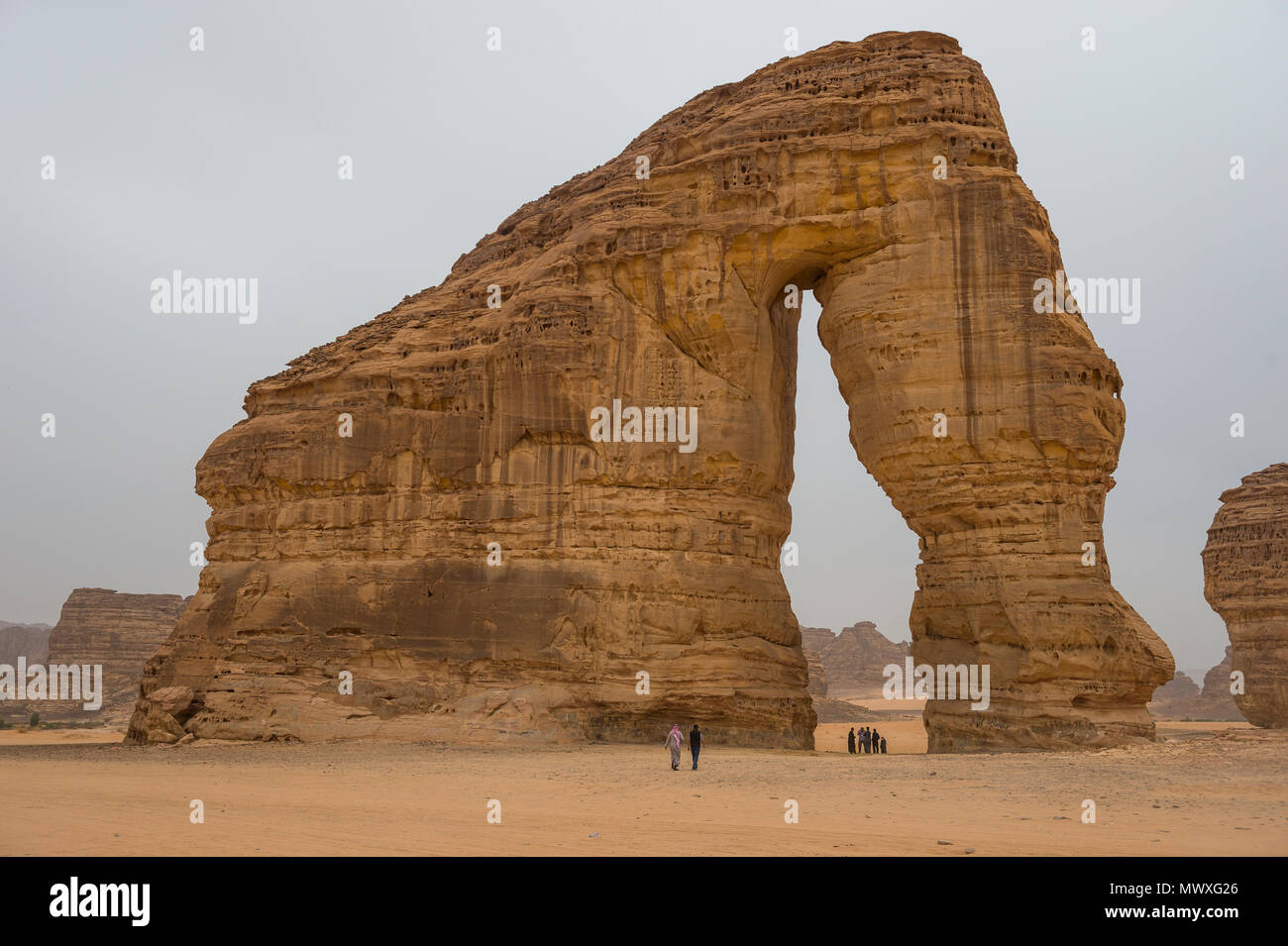 Locals standing in the giant arch of Elephant Rock, Al Ula, Saudi Arabia, Middle East Stock Photo