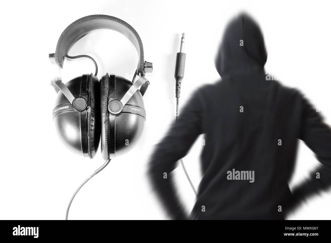 Headphone in background and black and white blurred vintage silhouette of young man with hooded sweatshirt. Dj concept. Stock Photo
