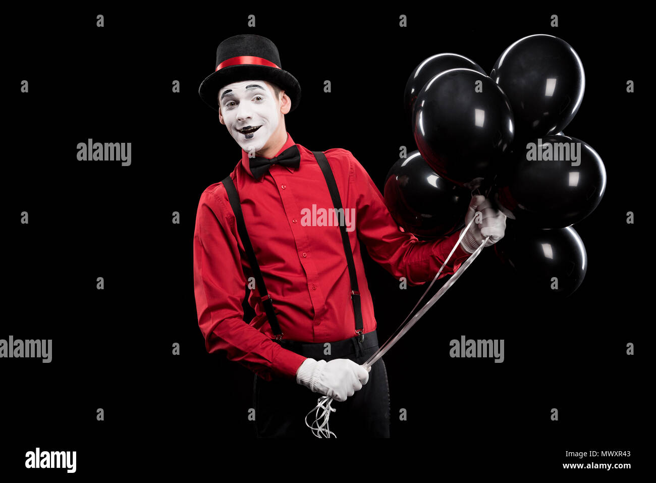 smiling mime holding bundle of black balloons isolated on black Stock ...