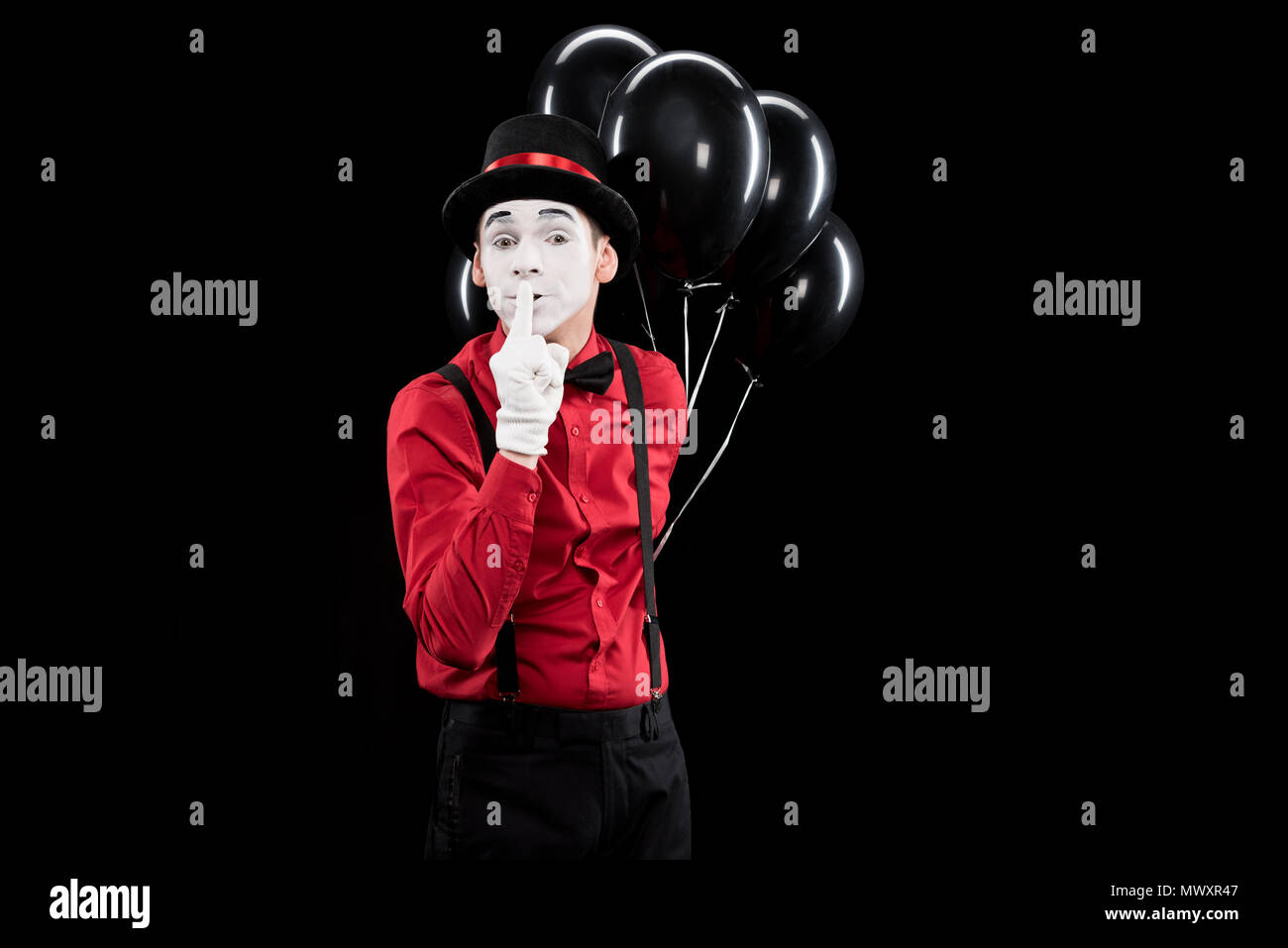 mime holding balloons and showing silence sign isolated on black Stock Photo