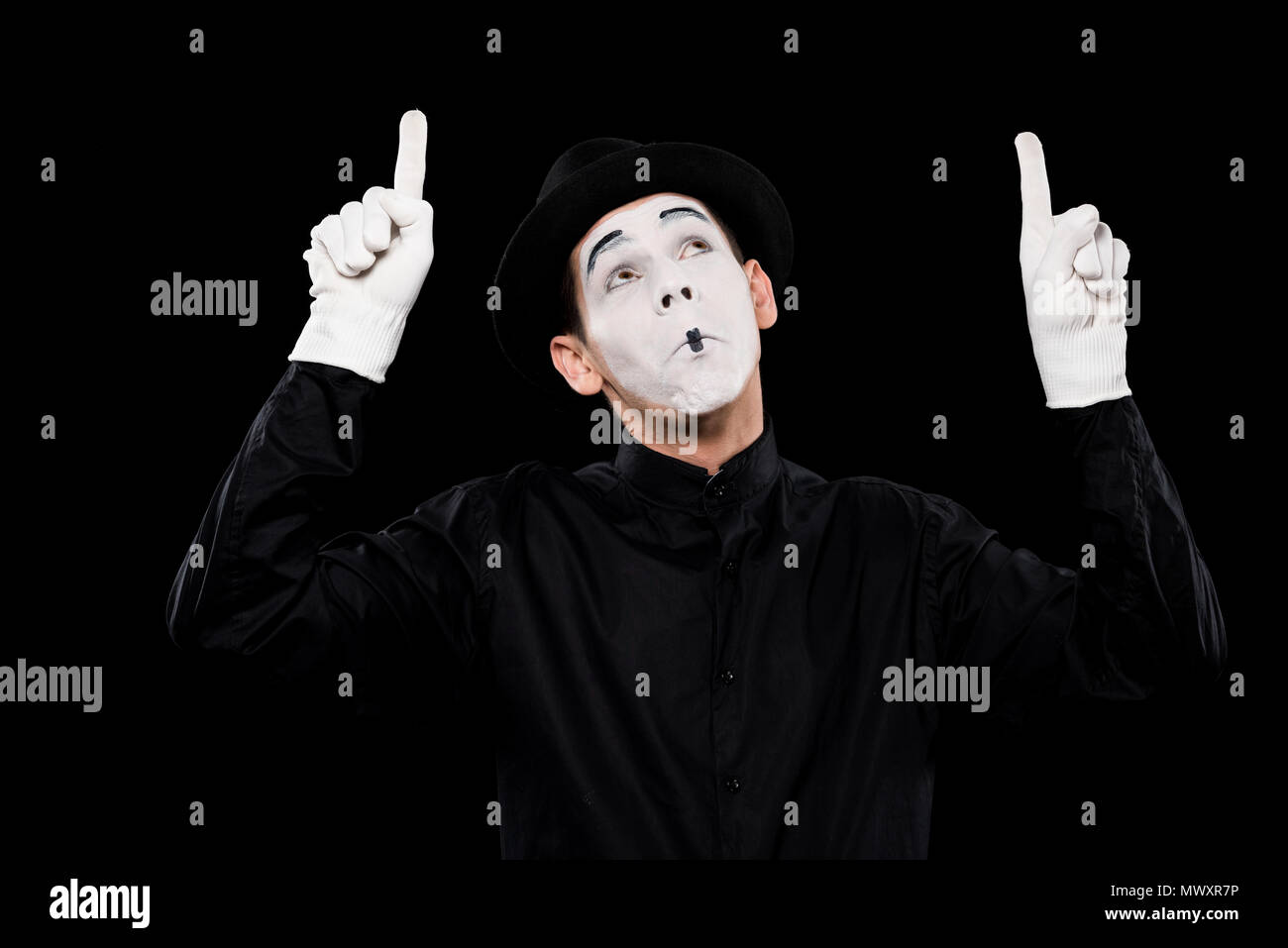 grimacing mime pointing on something isolated on black Stock Photo
