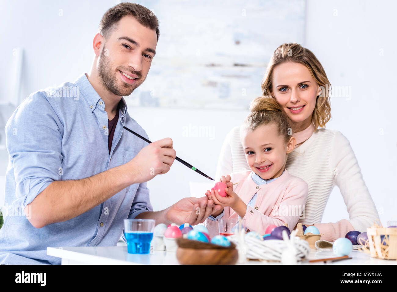 Father and daughter smiling while painting Easter eggs Stock Photo
