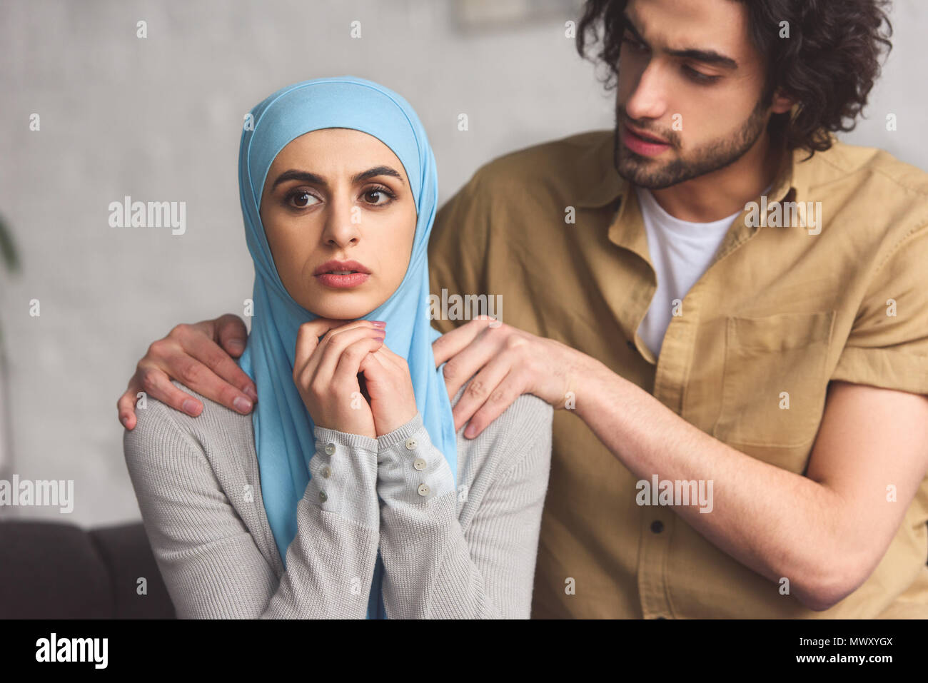 muslim boyfriend hugging worried girlfriend in hijab in living room ...