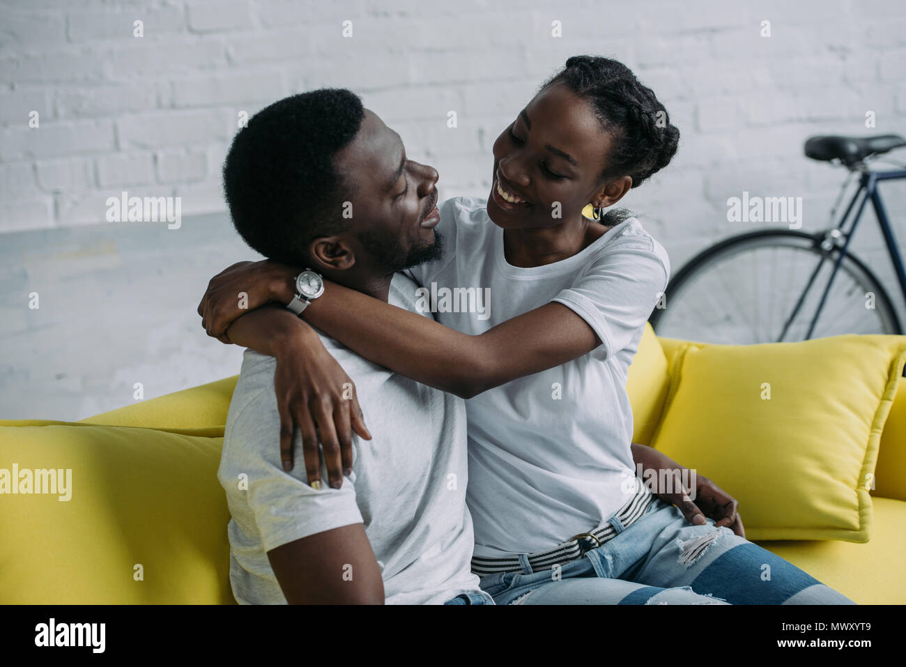 happy young african american couple hugging while sitting on sofa at ...