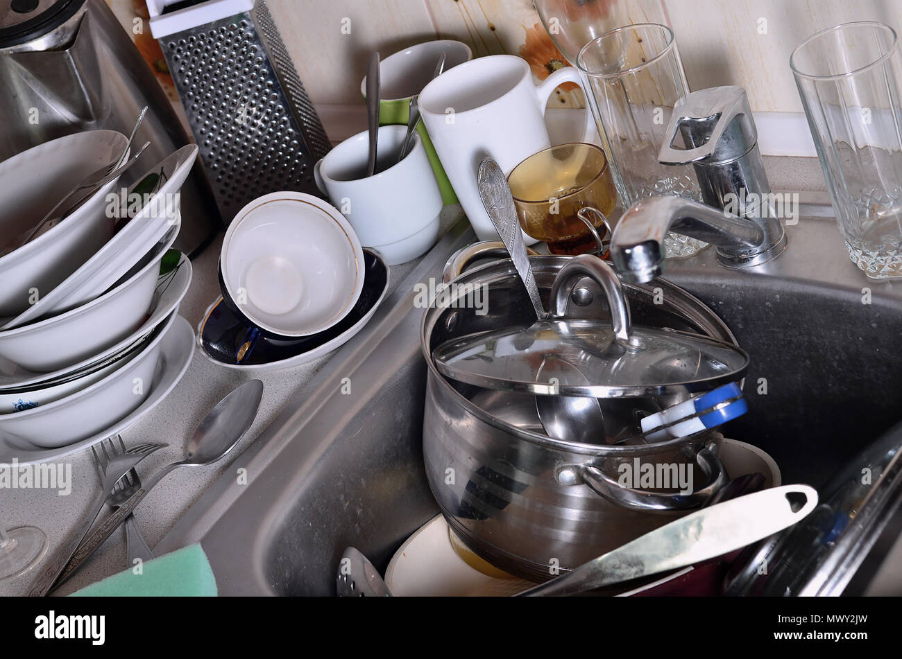 A huge pile of unwashed dishes in the kitchen sink and on the ...
