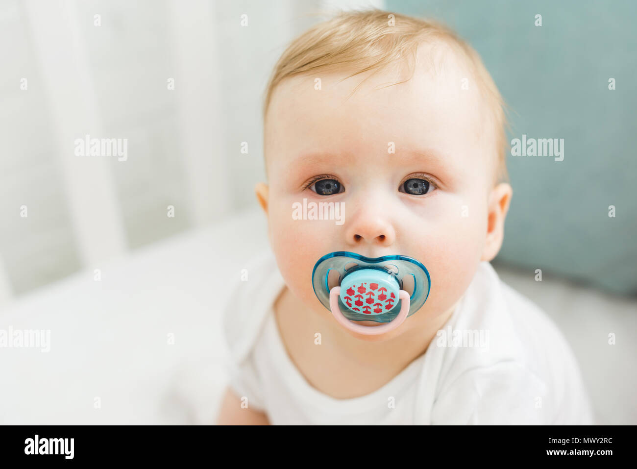 Portrait of infant with baby dummy in crib Stock Photo