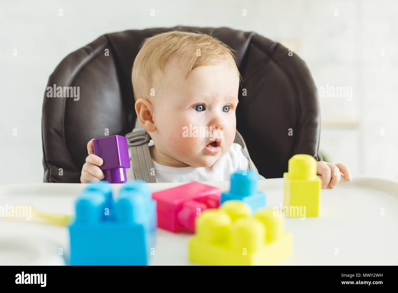 Adorable infant sititng in baby chair with plastic blocks Stock Photo