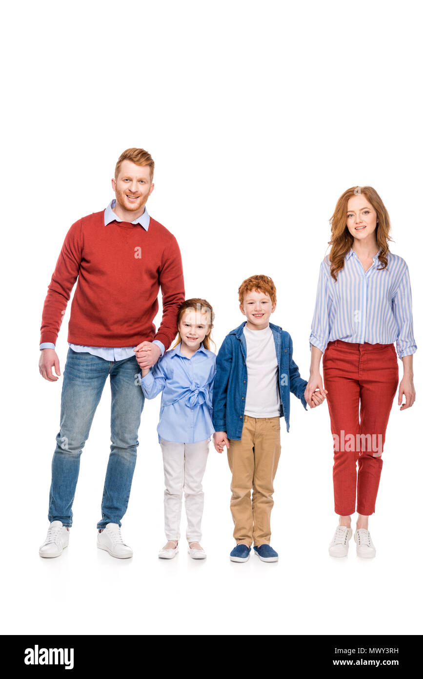 happy redhead family with two kids holding hands and smiling at camera isolated on white Stock Photo