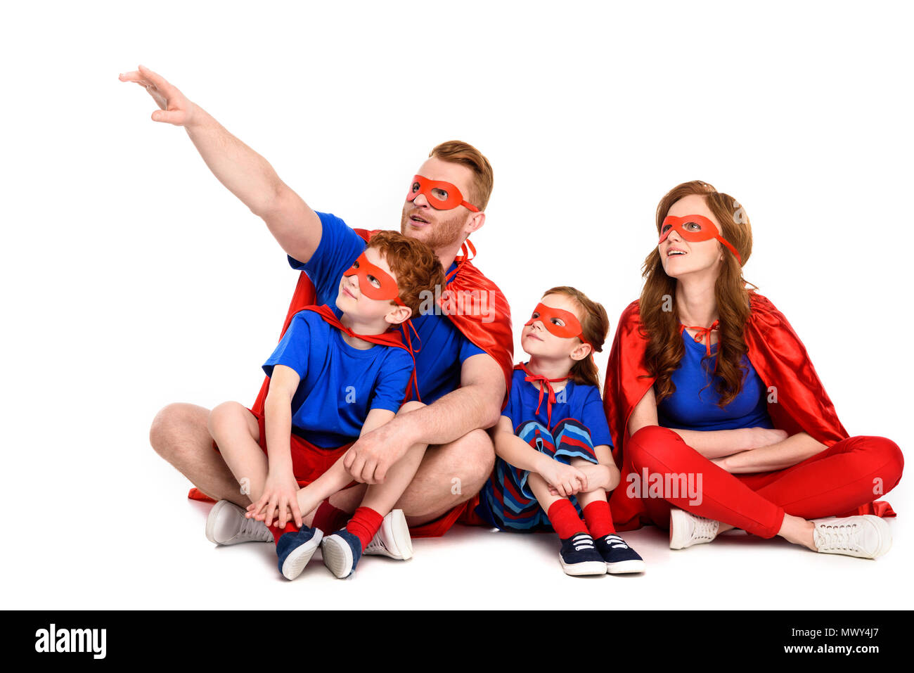 super family in costumes sitting together and looking away isolated on