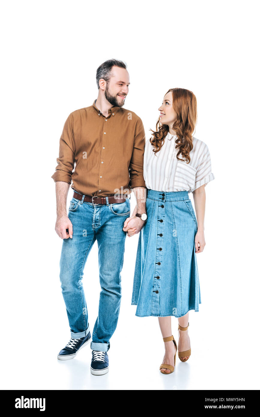 full length view of happy couple holding hands and smiling each other ...