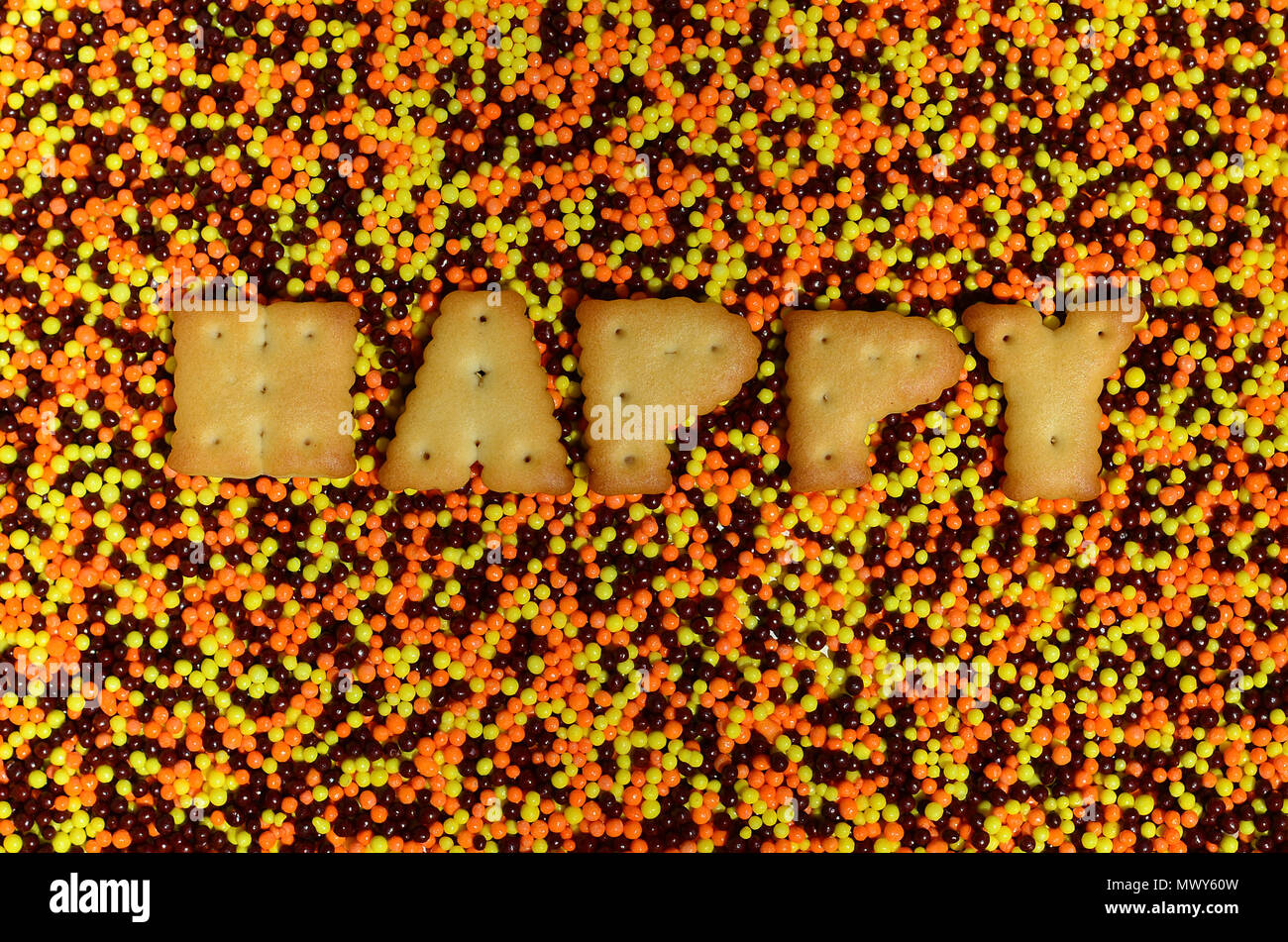 Happy. The word from the edible cracker letters lies on the glazed powder.  A huge number of sweet, colorful beads of very small size for decoration o  Stock Photo - Alamy