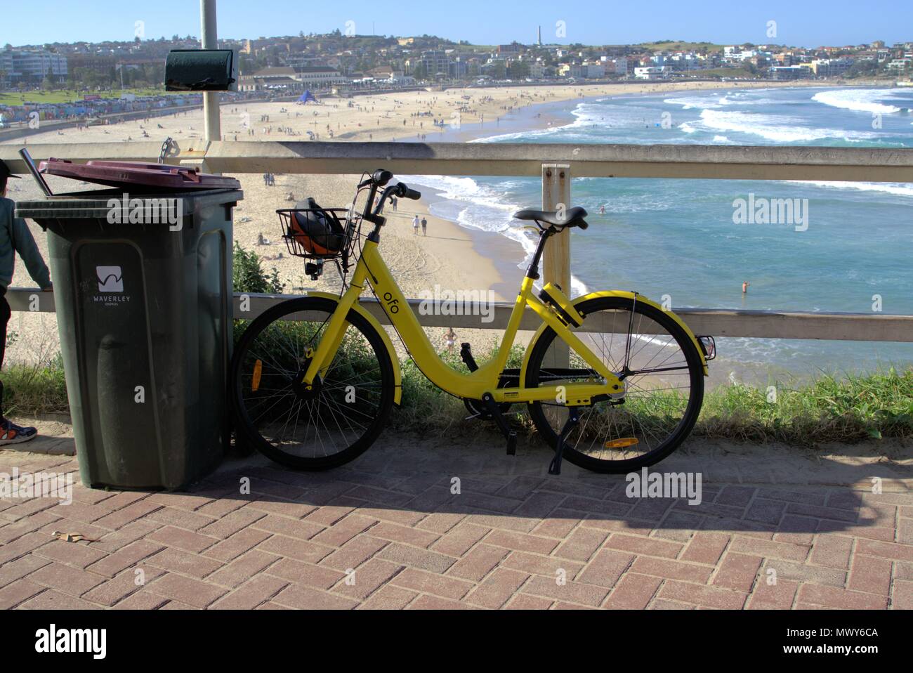 Ofo bike parked at Bondi beach in Sydney Australia. Ride sharing rental bicycle parked against garbage bin in Sydney. Illustrative editorial only. Stock Photo