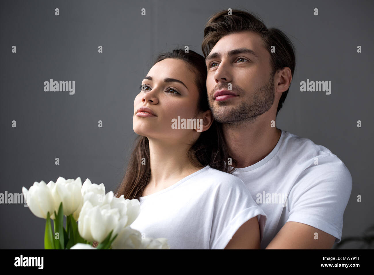 Romantic couple with tulips tenderly embracing in bedroom Stock Photo