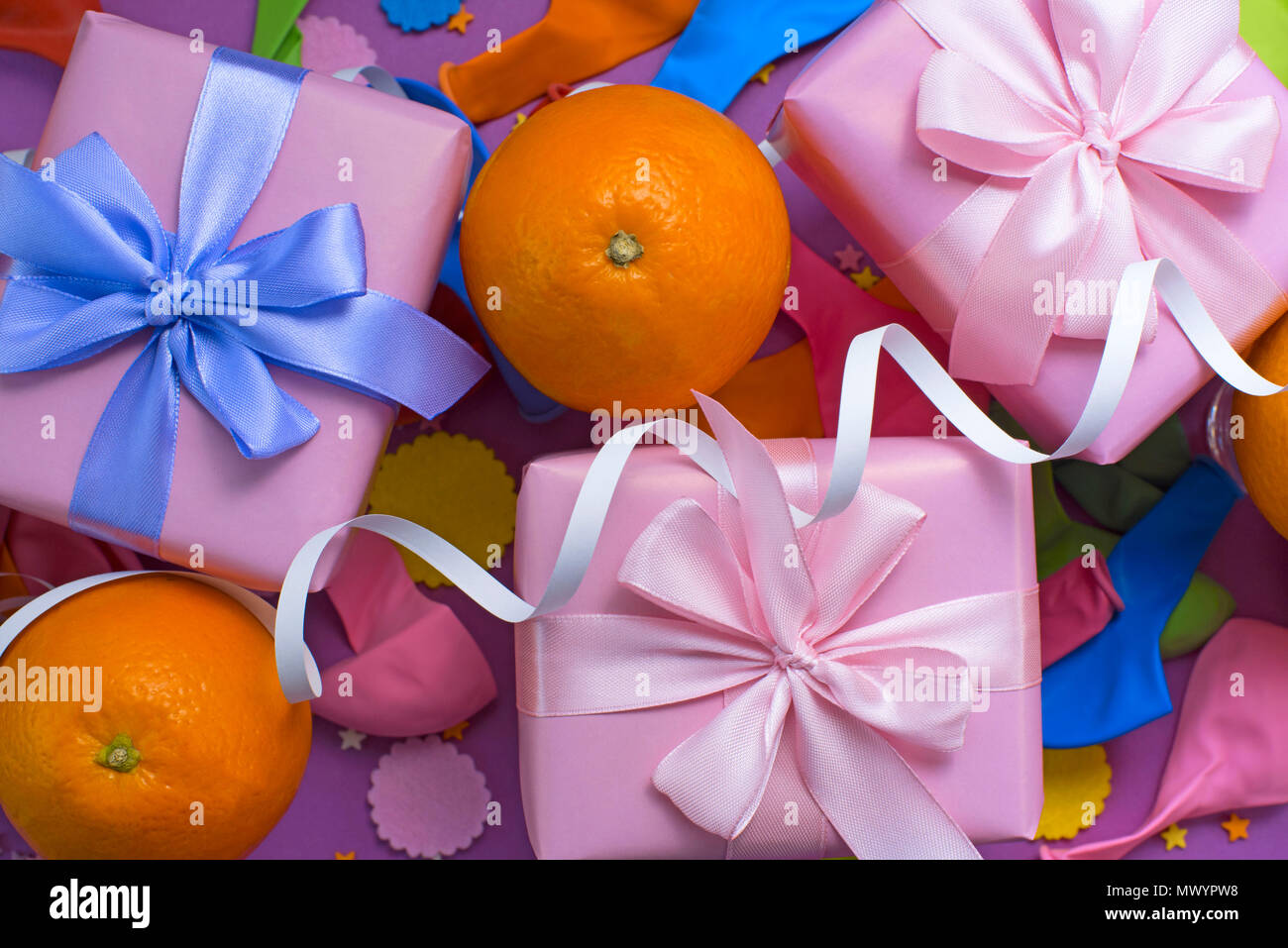 Decorative composition Three boxes with gifts Satin ribbon Bow Oranges Confetti Serpentine birthday party. The view from the top Stock Photo