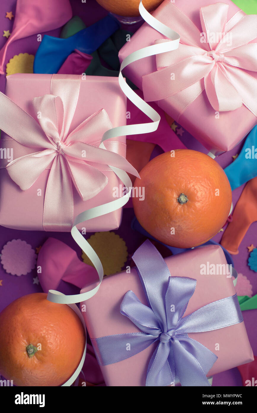 Decorative composition Three boxes with gifts Satin ribbon Bow Oranges Confetti Serpentine birthday party. The view from the top Vertical Toning Stock Photo