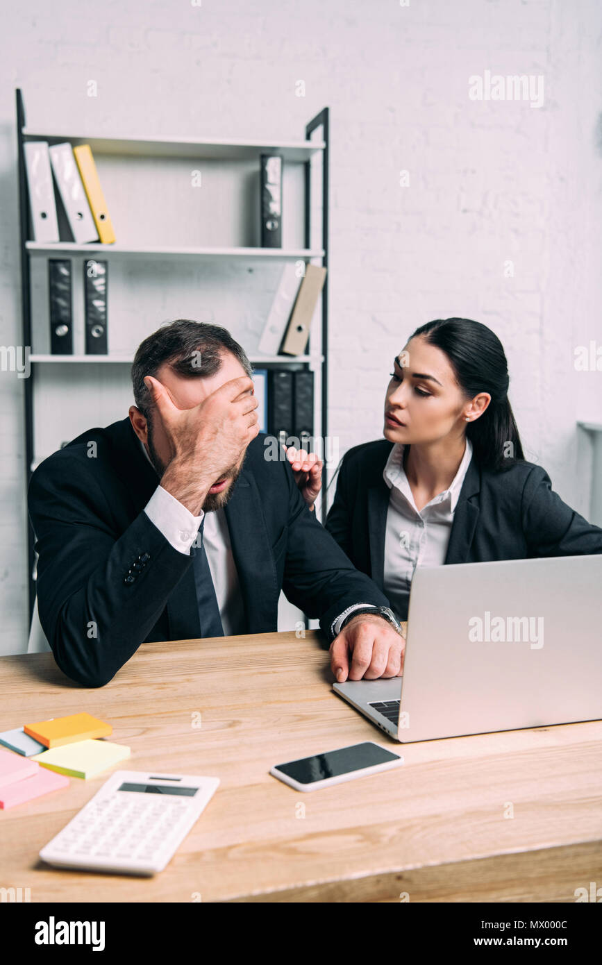 overworked businessman and business colleague at workplace with laptop ...