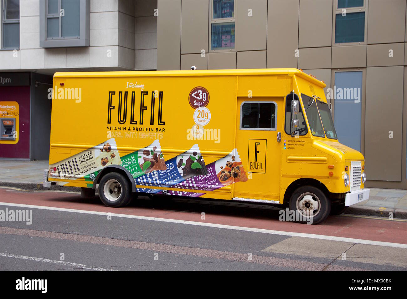 A parked yellow van that has a sponsored advert for Fulfil Vitamin Protein Bars on it Stock Photo