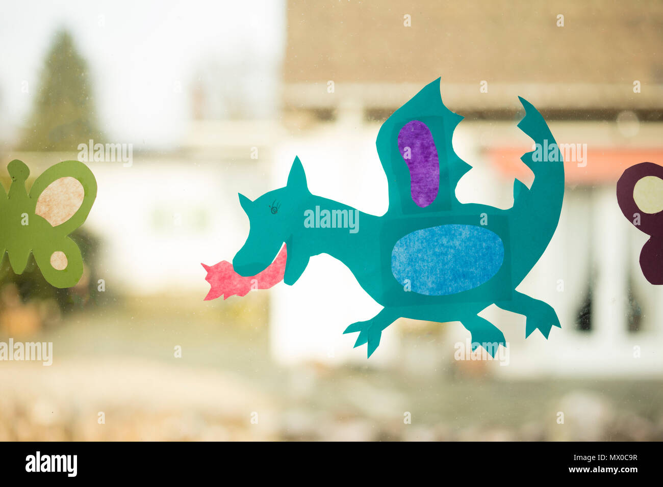 shape of a dragon made with paper as handicraft activity for children and placed on window glass. Stock Photo