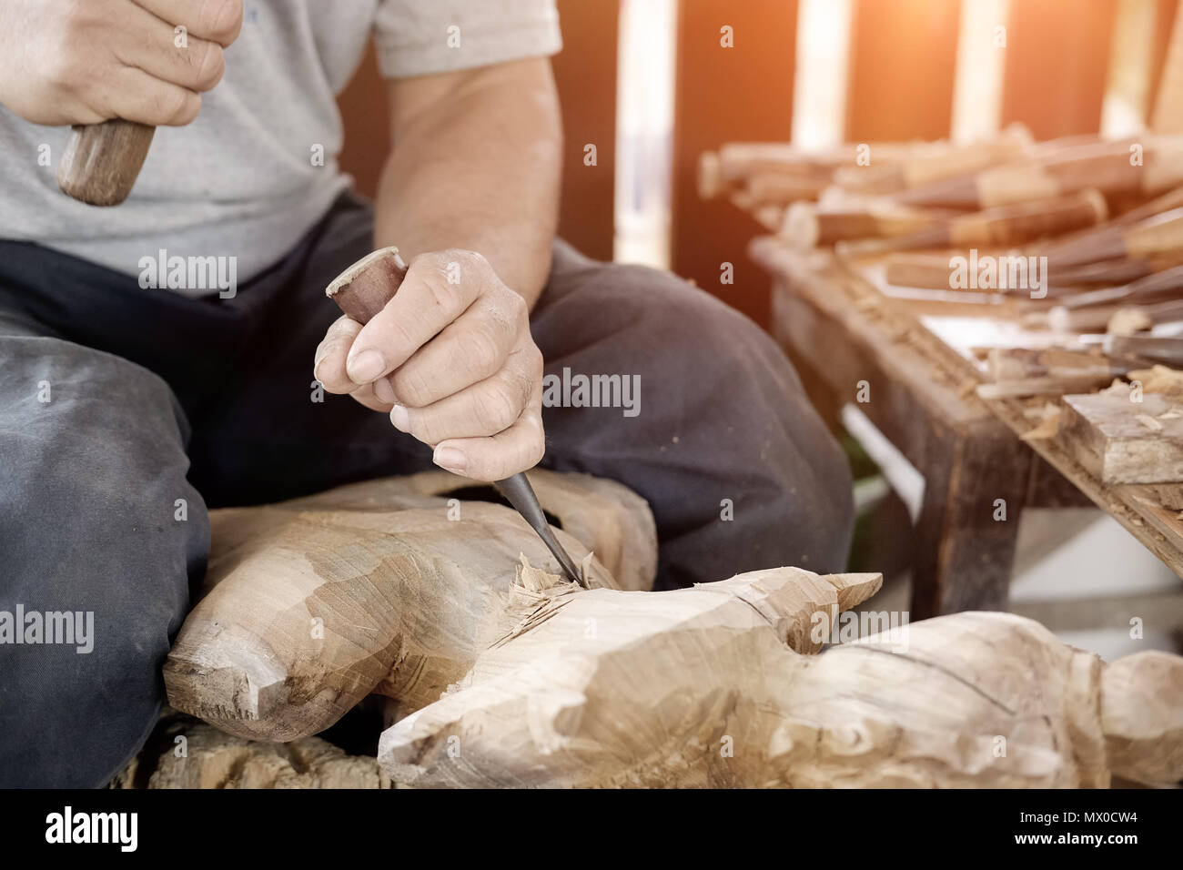 Closeup Old man Hands of craftsman wooden carve with a gouge in the hands on the workbench in carpentry Stock Photo
