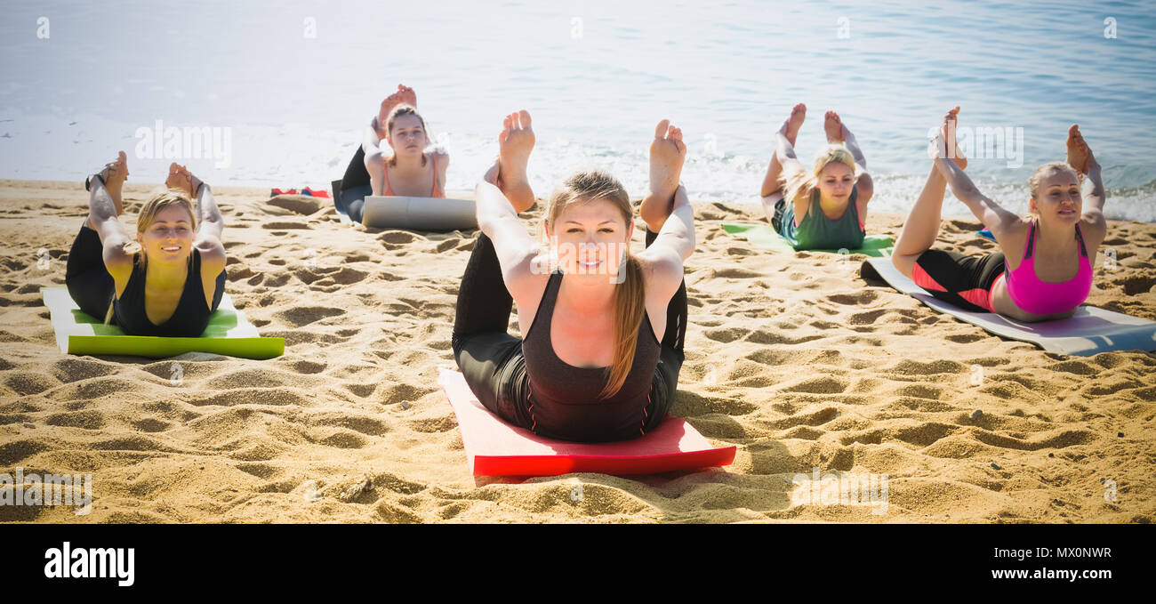 Asanas In Group Group of smiling women exercising yoga asanas on sea beach Stock Photo ...