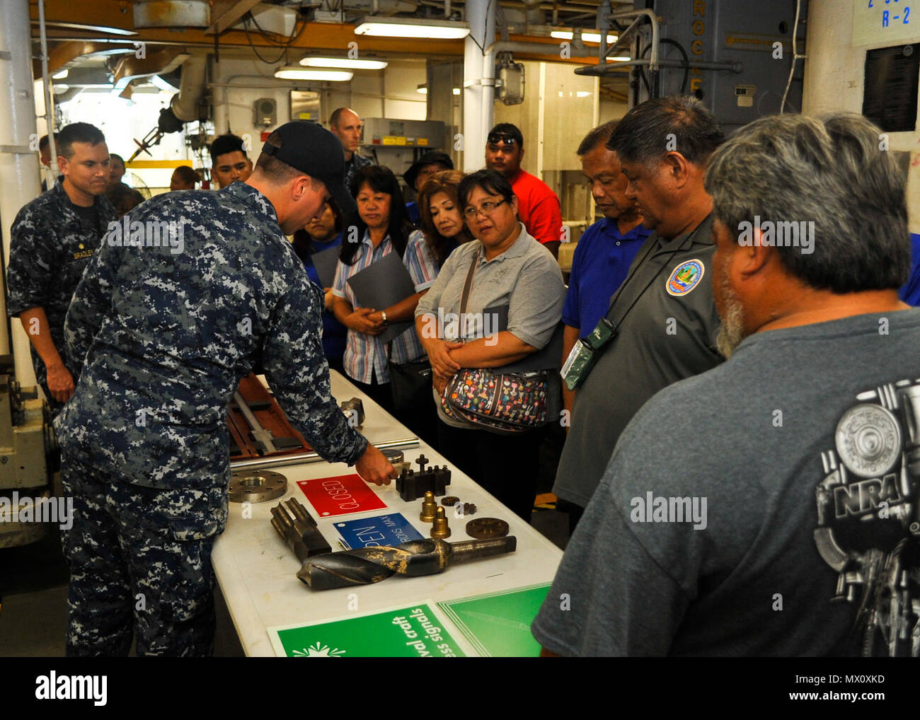 POLARIS POINT, Guam (May 1, 2017) Machinist’s Mate Fireman Kyle Drummond explains the capabilities of the fleet machine shop aboard the submarine tender USS Emory S. Land (AS 39) to Asan-Maina mayor Frankie Salas, Dededo mayor Melissa Savares, Merizo mayor Ernest T. Chargualaf, and their respective staffs. Asan-Maina, Dededo, and Merizo are Land’s sister villages, partnerships forged to strengthen the relationship between the Navy and the local Guam community. Land, homeported in Guam, provides maintenance, hotel services and logistical support to submarines and surface ships in the U.S. 5th a Stock Photo