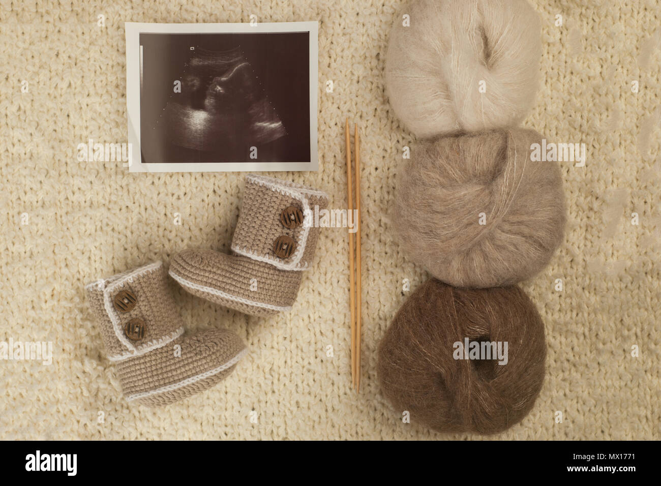 Children's shoes and ultrasound of the baby's fetus with a needles and yarn on soft knitted background. Cozy, warm winter and Happy pregnancy concept Stock Photo
