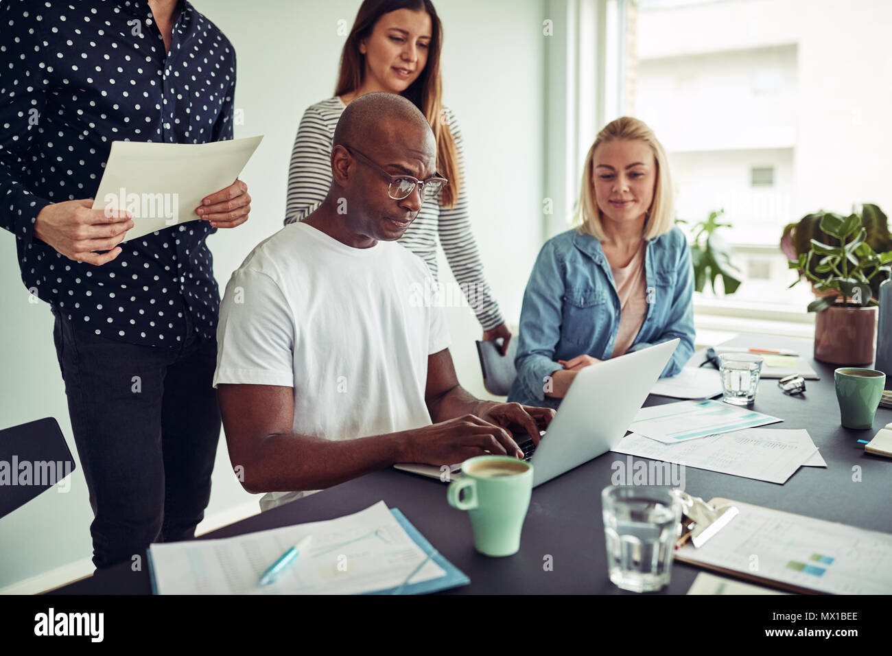 Focused group of diverse businesspeople working together over a laptop ...