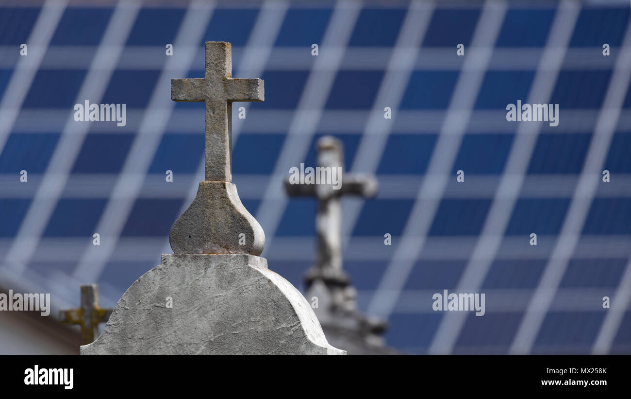 Stone crosses on graves with blurred solar panels in the background Stock Photo