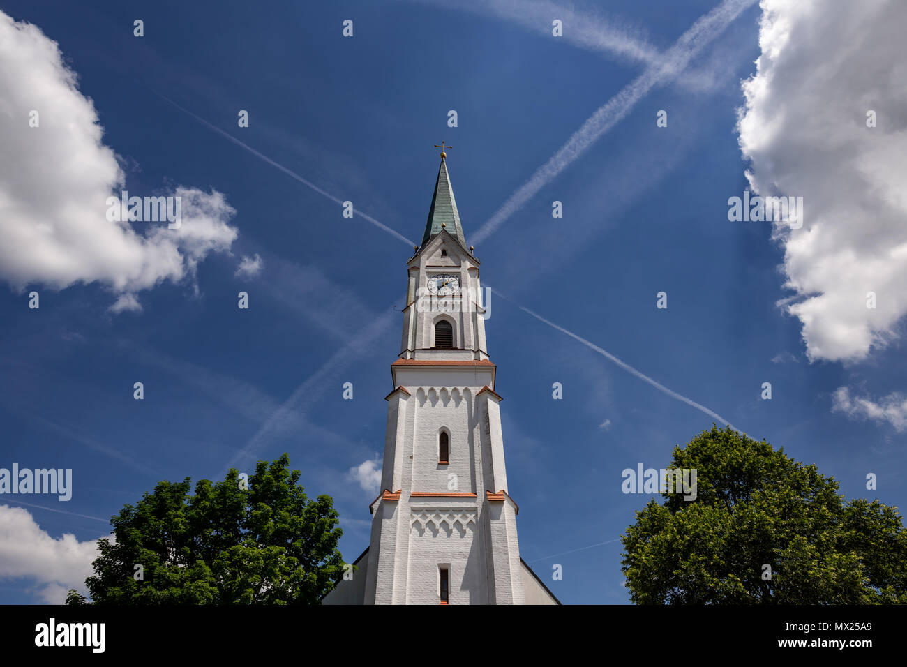 St.-Georg church in Gerzen, Bavaria, Germany with blue sky, clouds and contrails in the background Stock Photo
