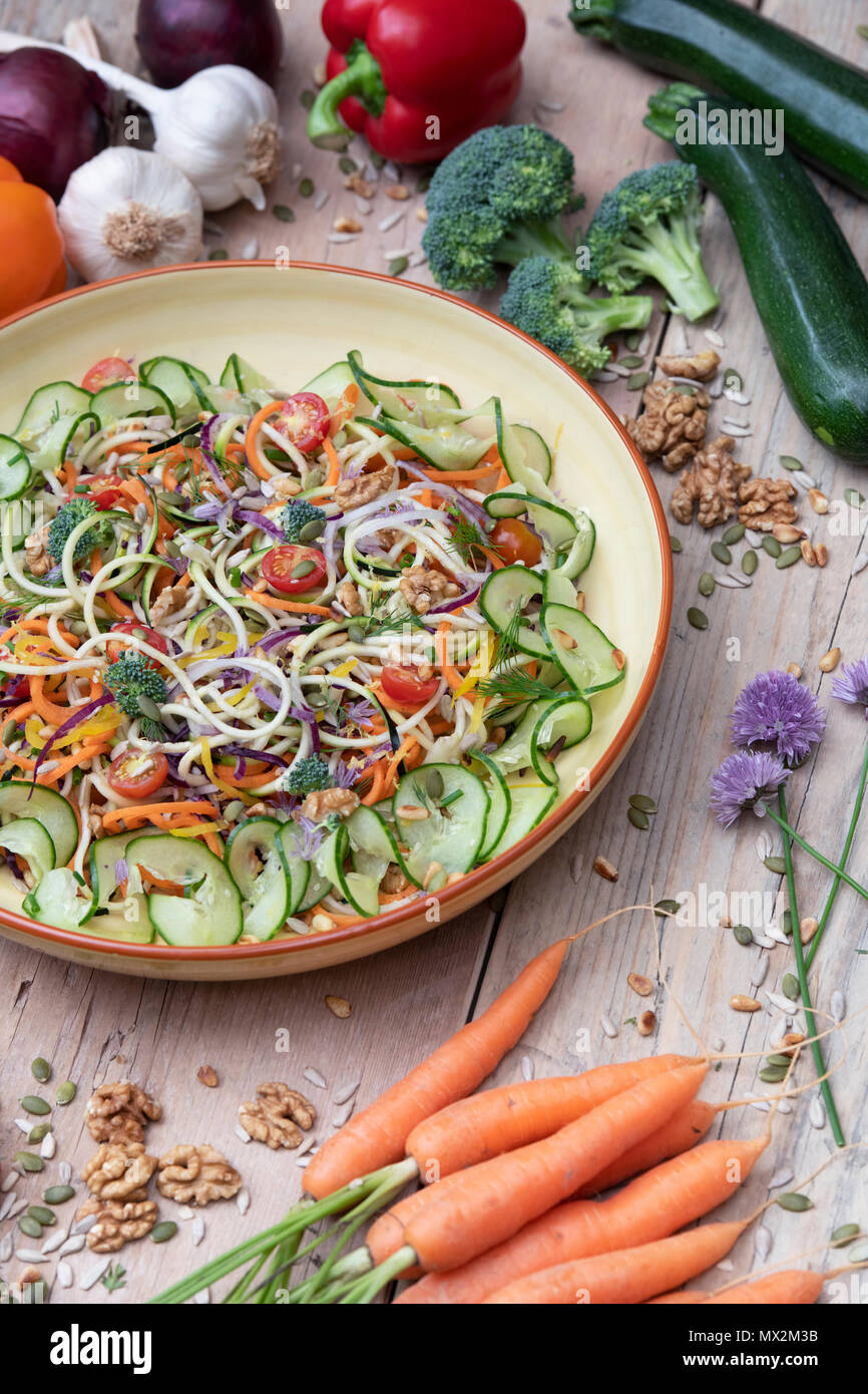 Spiralized Vegetable Salad in a bowl surrounded by vegetables on wood Stock Photo