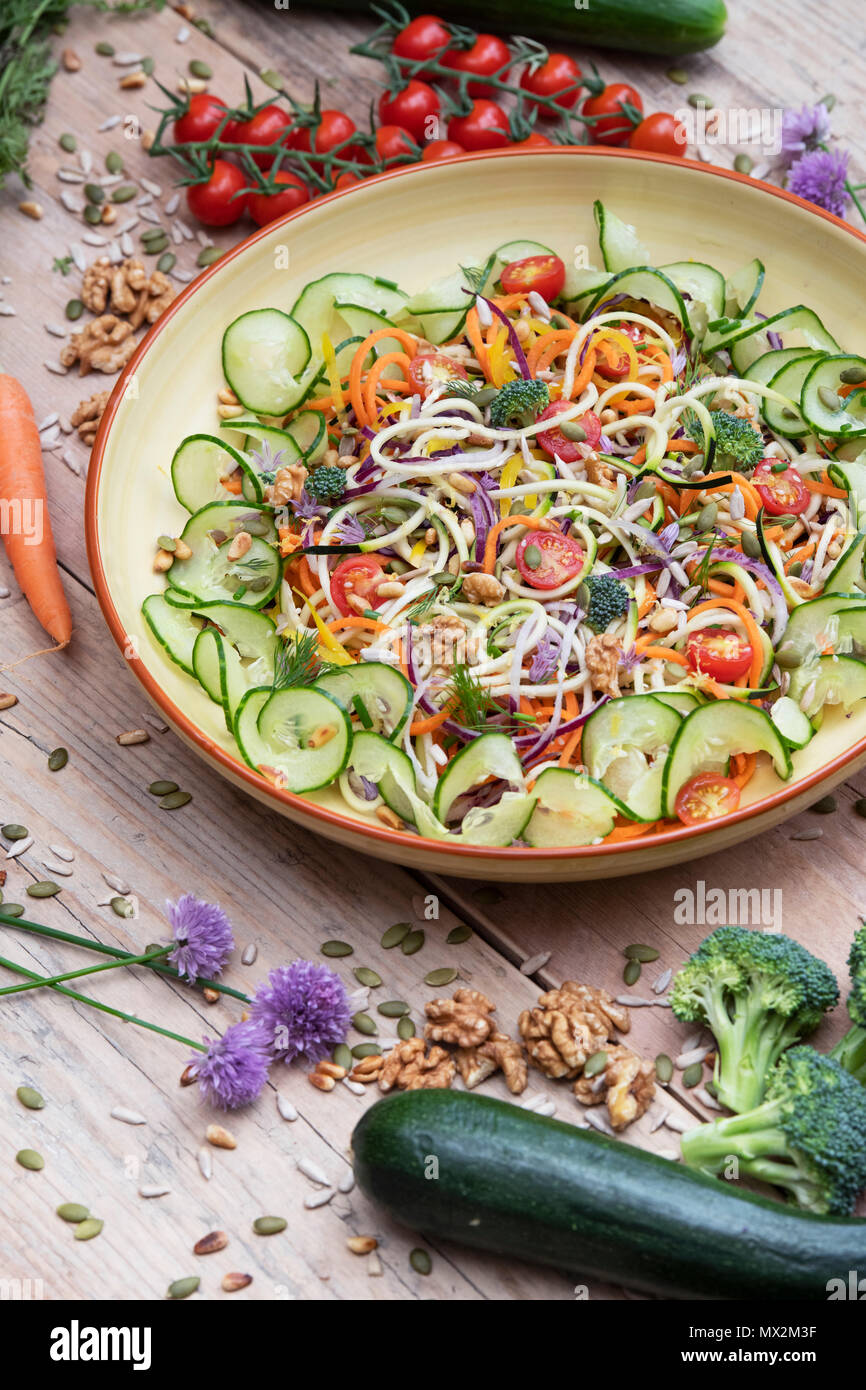 Spiralized Vegetable Salad in a bowl surrounded by vegetables on wood Stock Photo