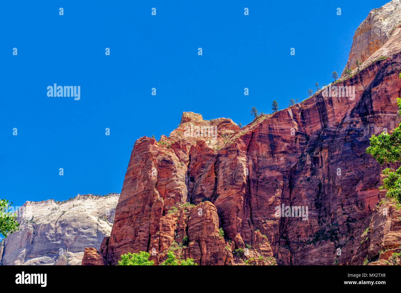 Looking at at tall solid rock mountain, red orange in color under a clear blue sky. Stock Photo