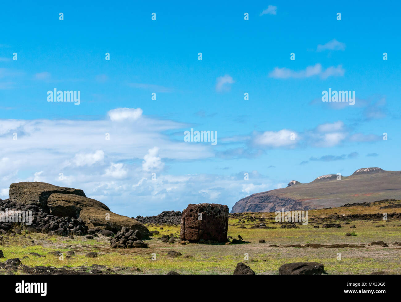 Ahu Te Pito Kura with fallen Moai and view of Pike extinct volcano, Easter Island, Rapa Nui, Chile, with blue sky Stock Photo
