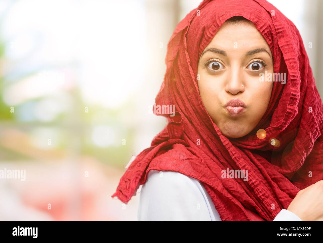Young arab woman wearing hijab puffing out cheeks, having fun making funny face Stock Photo