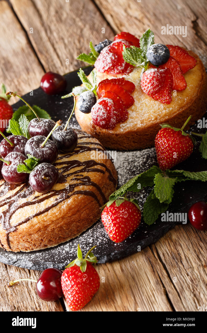 Freshly baked two cakes with chocolate, mint, strawberry, cherry and blueberry close-up on the table. vertical Stock Photo