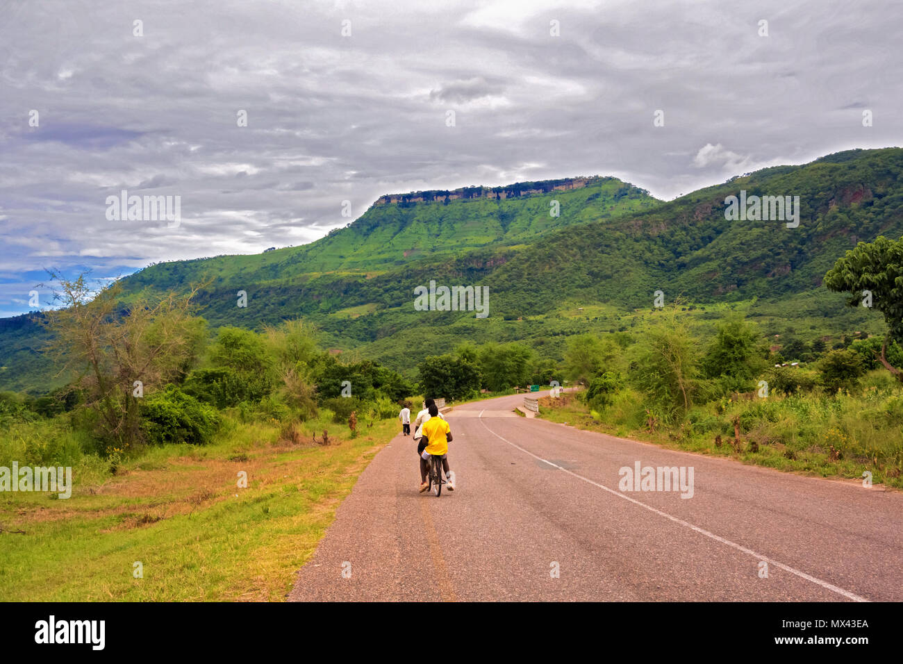 Khondowe, Malawi - March 24, 2015: People are riding bicycle on the road in small village in Khondowe, Malawi. The village is located near lake Malawi Stock Photo