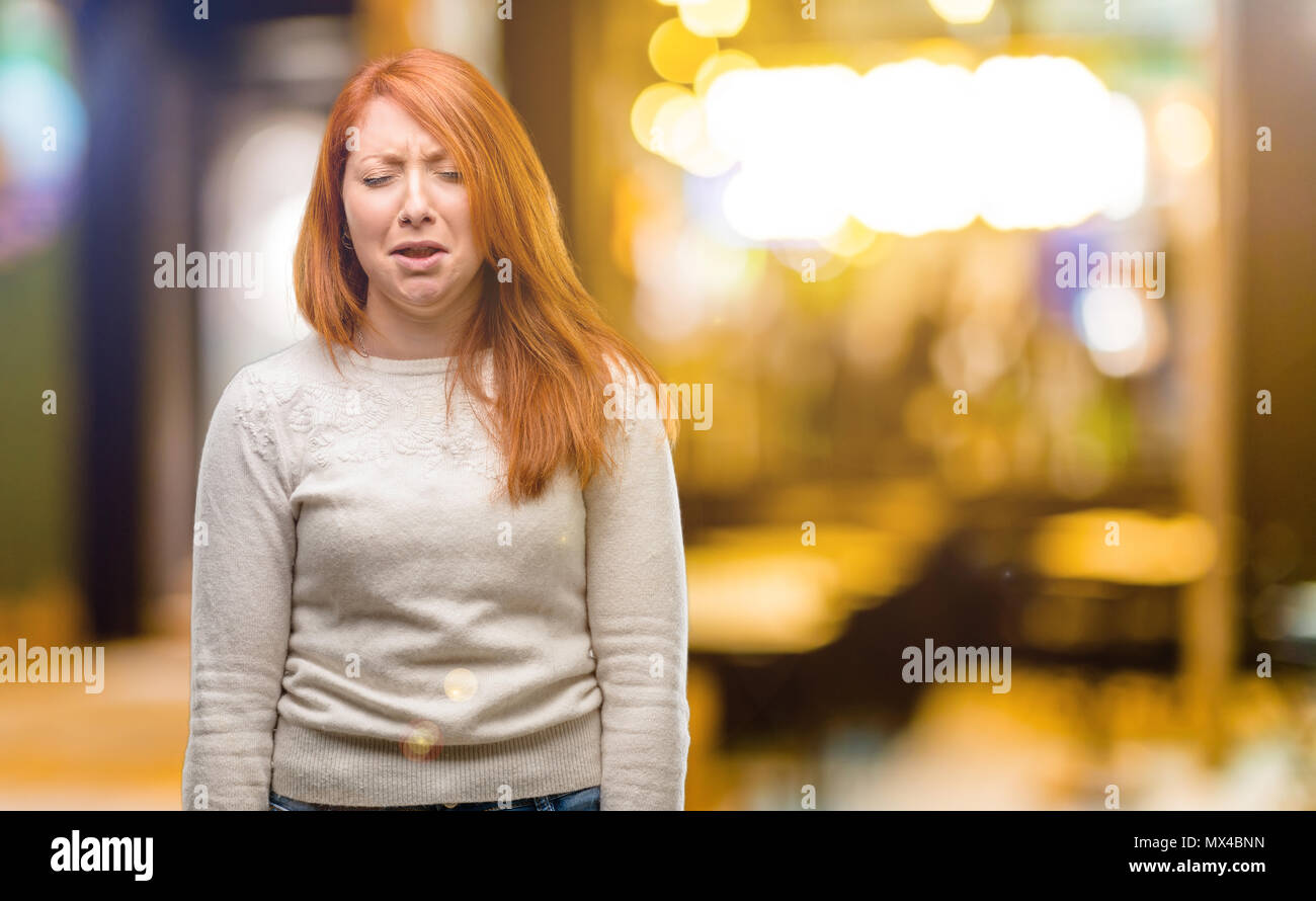 Beautiful young redhead woman crying depressed full of sadness expressing sad emotion at night Stock Photo