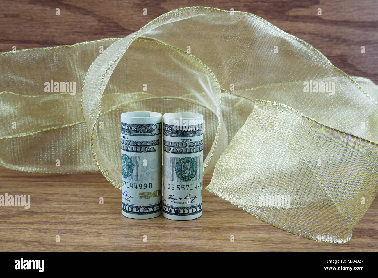 Profit and success are reflected with dollar currency placed in swirls of golden ribbon on wood grain background Stock Photo