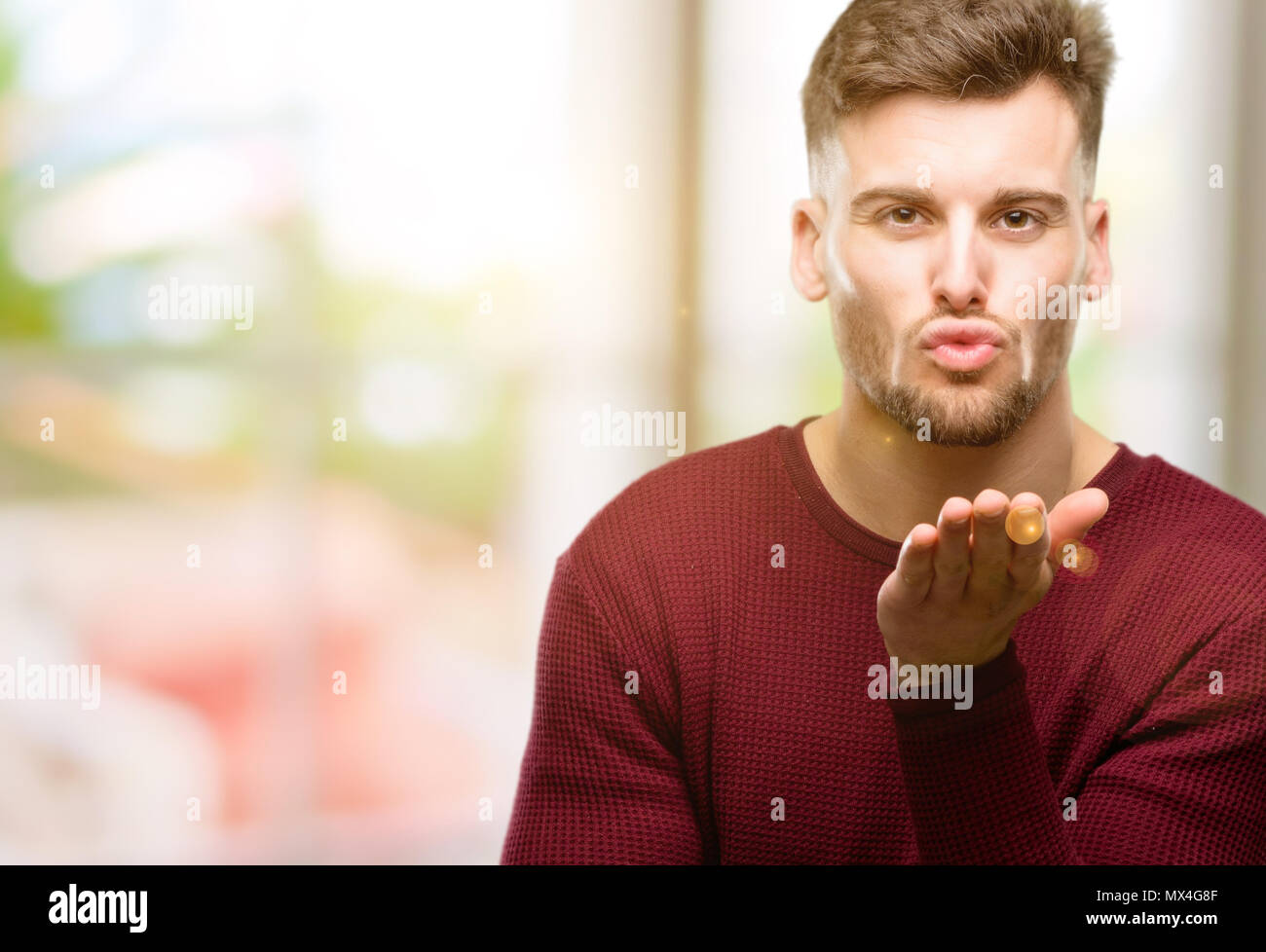 Handsome young man expressing love, blows kiss at camera, flirting