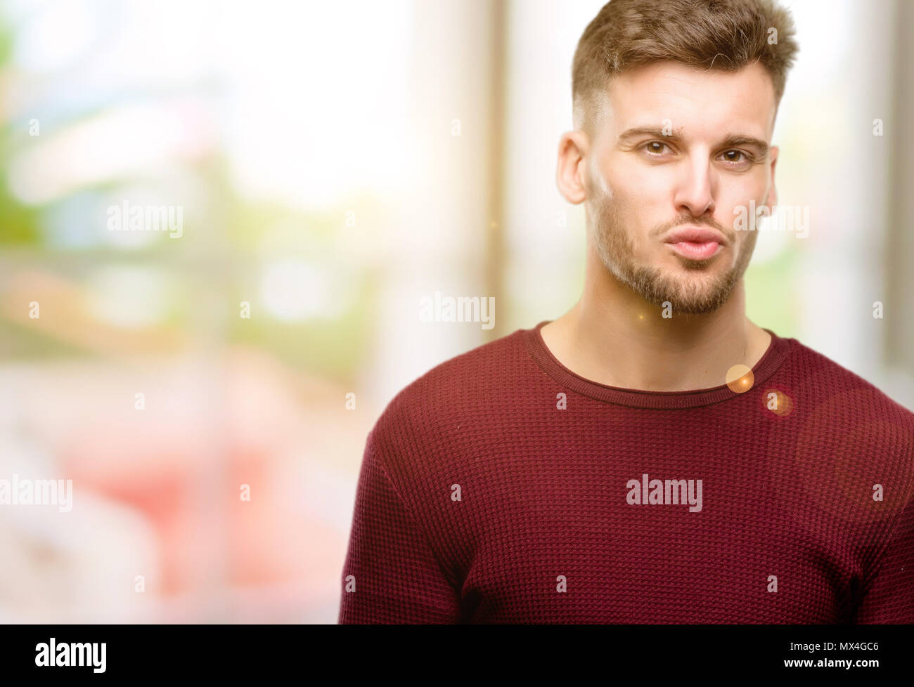 Handsome young man expressing love, blows kiss at camera, flirting
